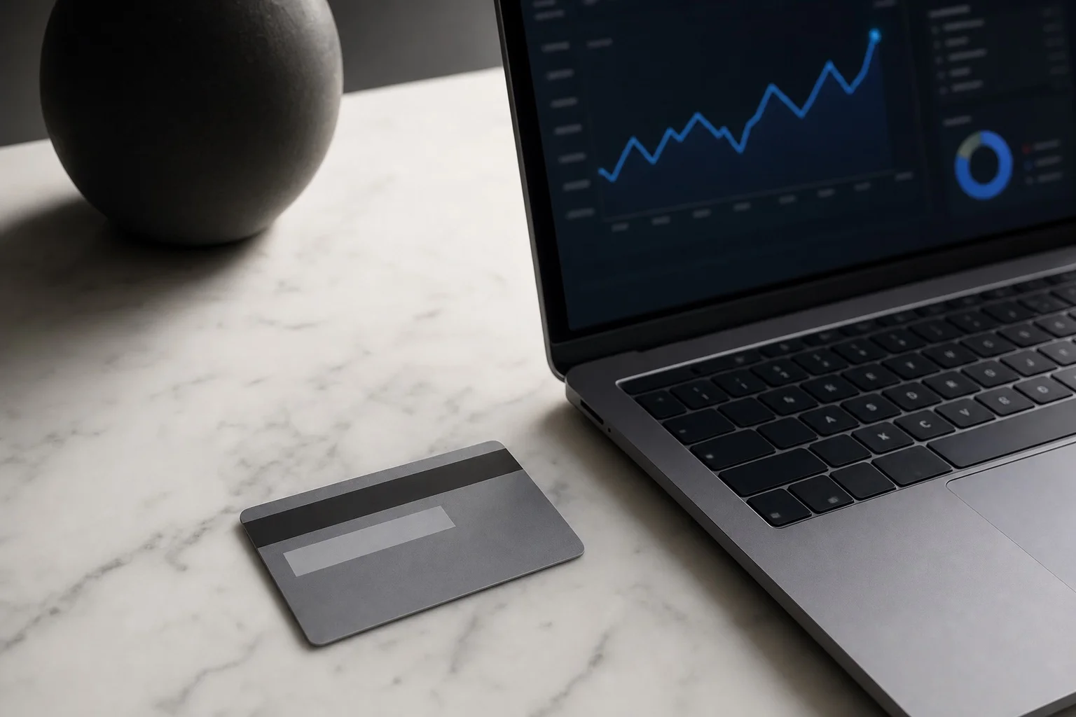 Credit card on marble next to a laptop showing payment analytics